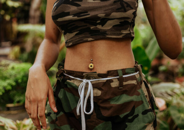 Woman wearing military uniform with belly button piercing. This is for the post How Long Does a Belly Button Piercing Take to Heal?